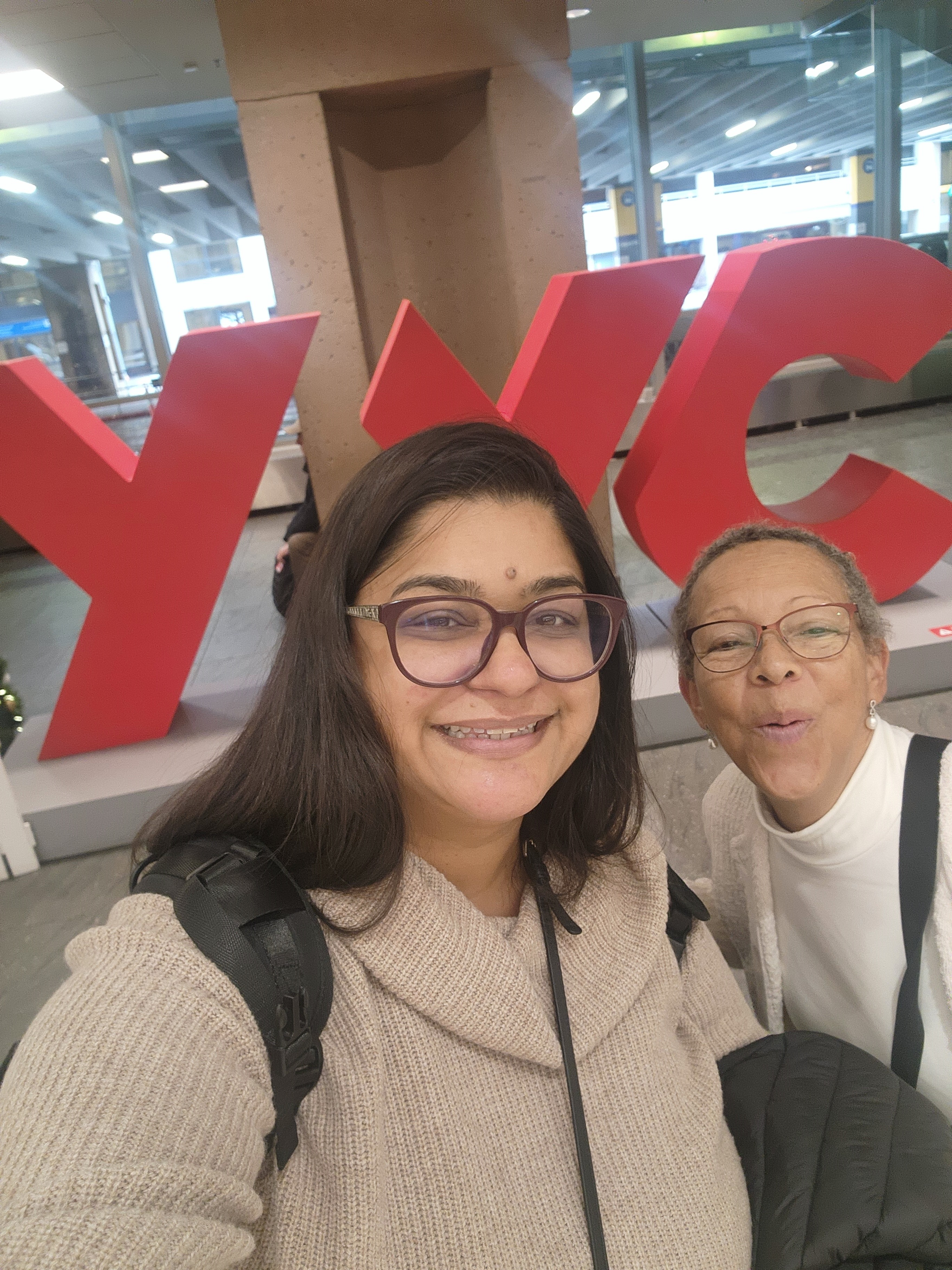 Nadia and Fatima pose in front of airport sign