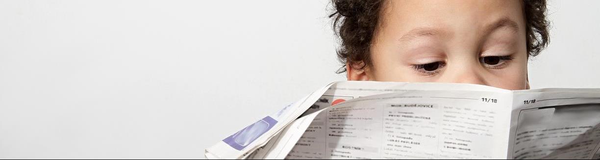 Little boy reading newspaper