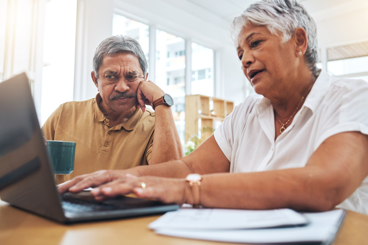 Older couple working on computer with frustration